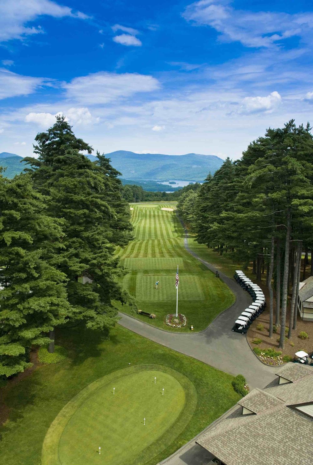 The Sagamore golf course from above: a striped fairway running toward Lake George and the mountains