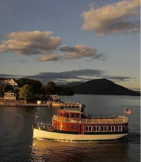 A red and cream steamboat on Lake George at sunset